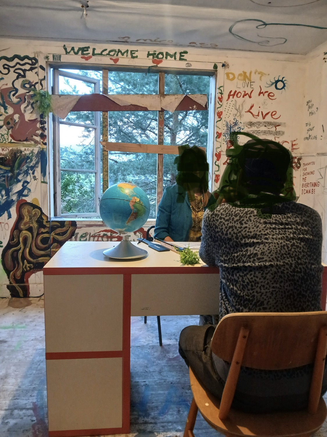 Two guests at the desk inside The Interview, with Welcome Home painted above the window